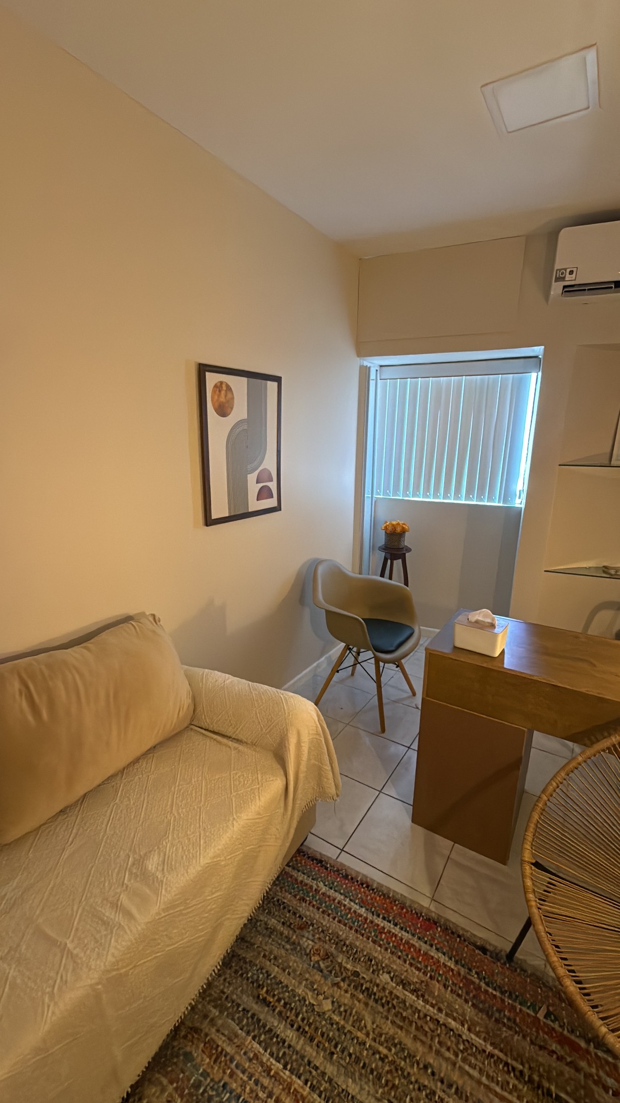 Consultório com sofá, poltrona e mesa em ambiente acolhedor